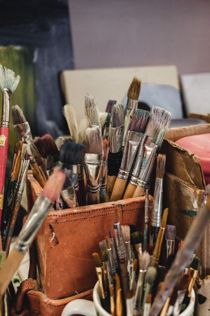 Abundant paintbrushes in various sizes and shapes in an artist's studio setting.